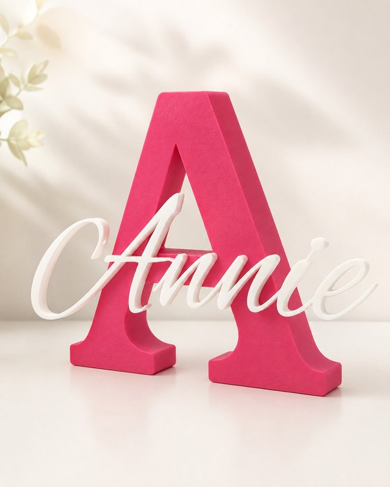 A pink 3D printed letter A with the name Annie in white cursive script inset across its face